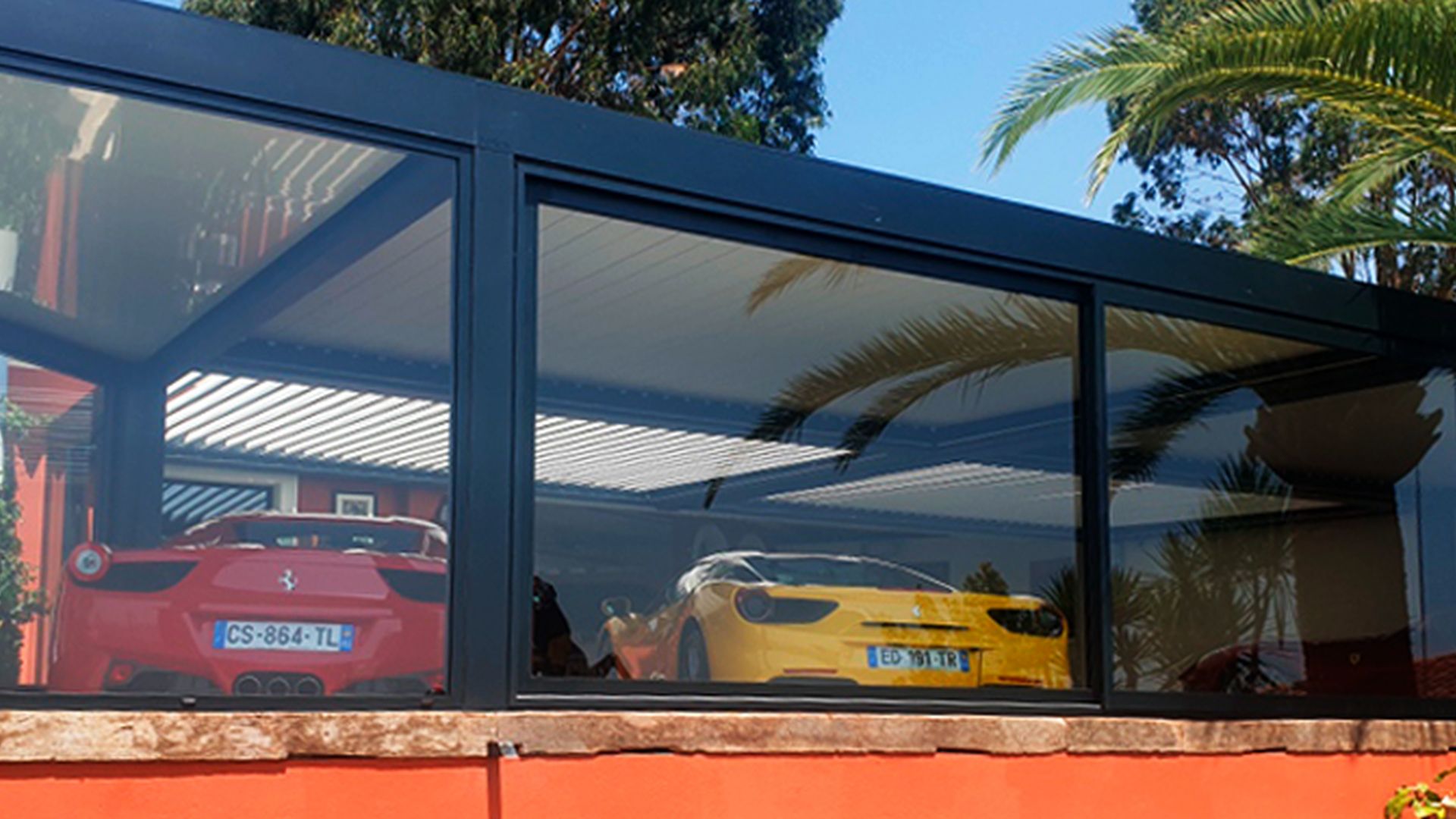 Pérgola como garaje con acristalado visto desde el exterior con dos deportivos aparcados con comodidad