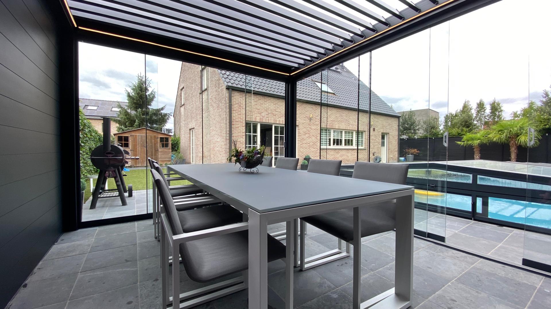 Pérgola terraza con mesa y sillas de comedor exterior que dan a la piscina y al jardin con acristalado piscina