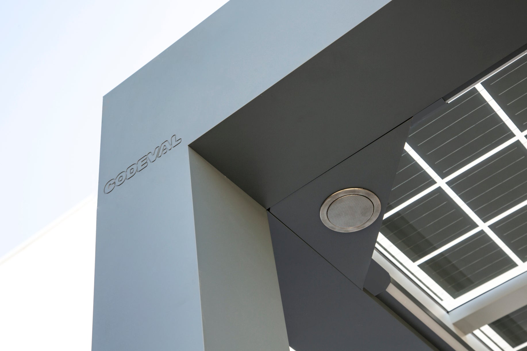 Corner detail of a photovoltaic pergola seen from below with an LED spotlight