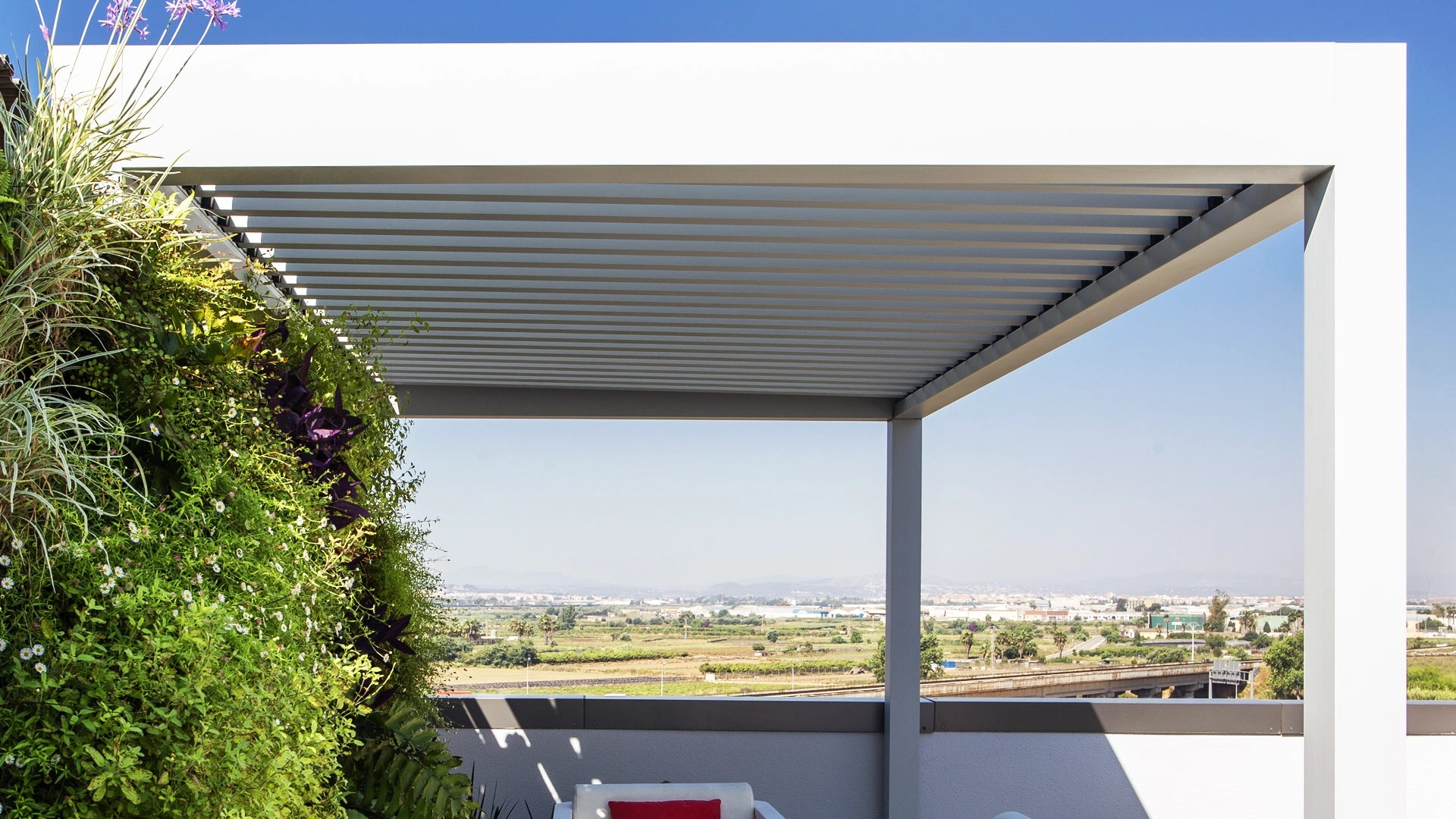 Pérgola Bioclimática en Azotea con zona ajardinada y mobiliario de exterior.