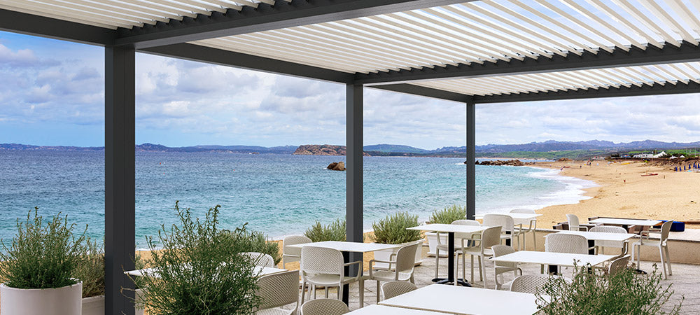 Pérgola bioclimática de lamas orientables en terraza de restaurante con vistas al mar